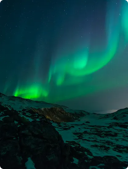 Green aurora lights above snowy mountains