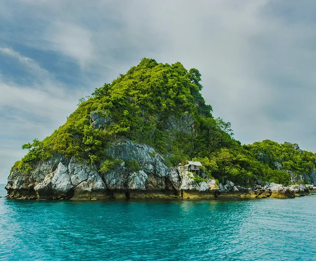 Pulau tropis hijau di atas air biru jernih